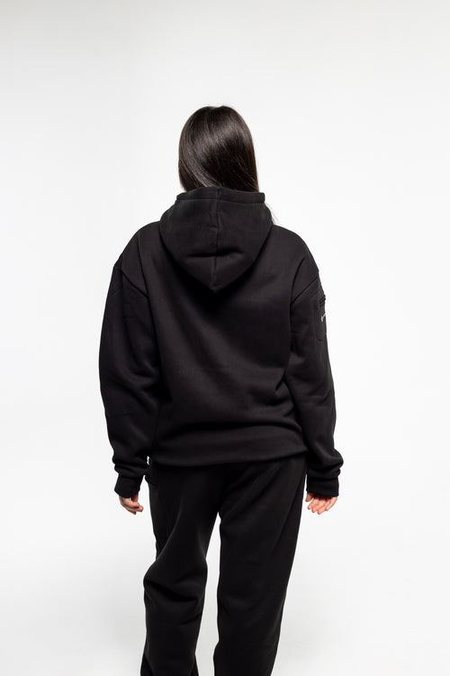 Person wearing a black hoodie and pants on a white background