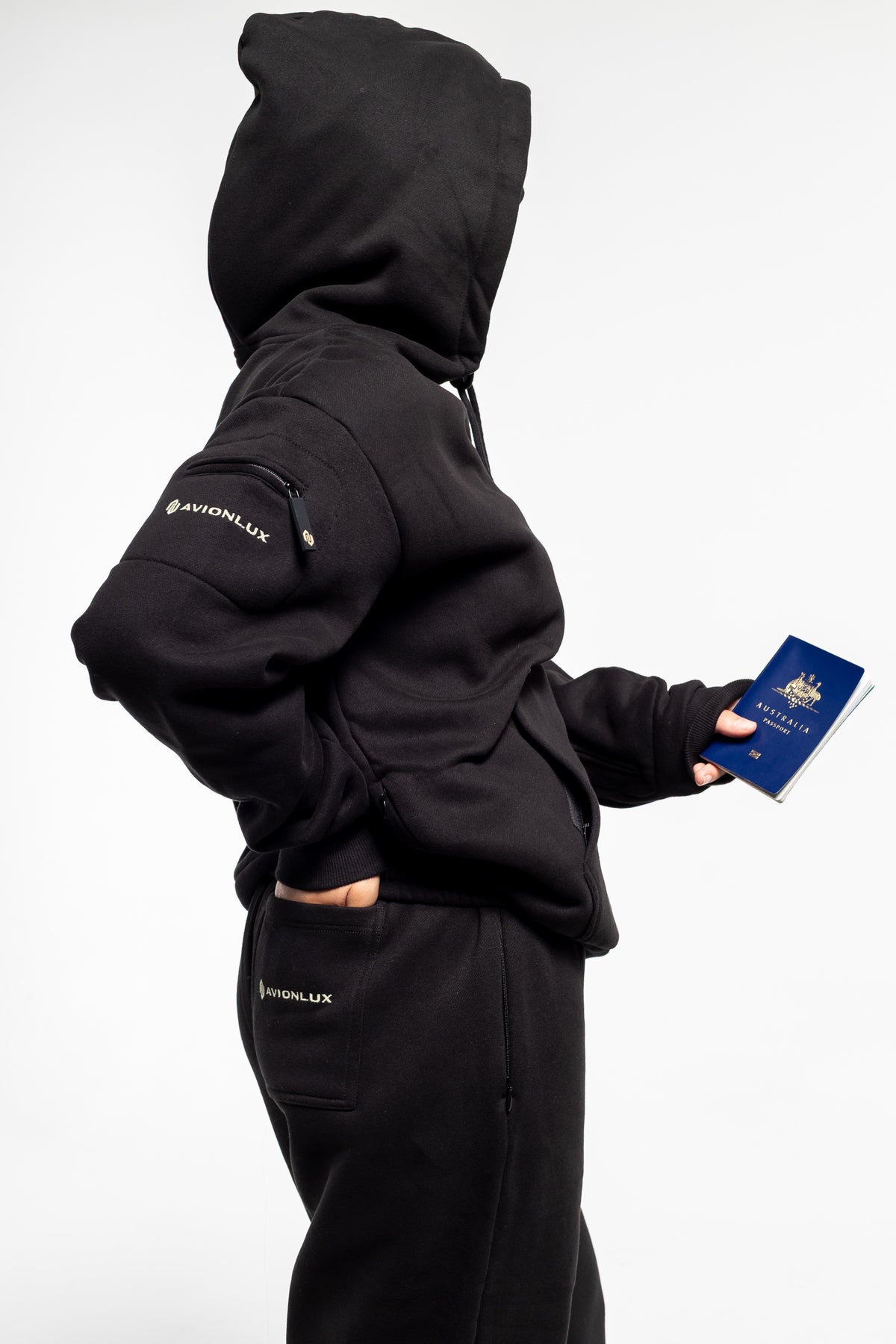 Person wearing a black hoodie with 'AVIONLUX' branding, holding a passport.